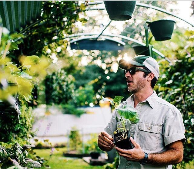 Marcus under the hoop house holding a seedling